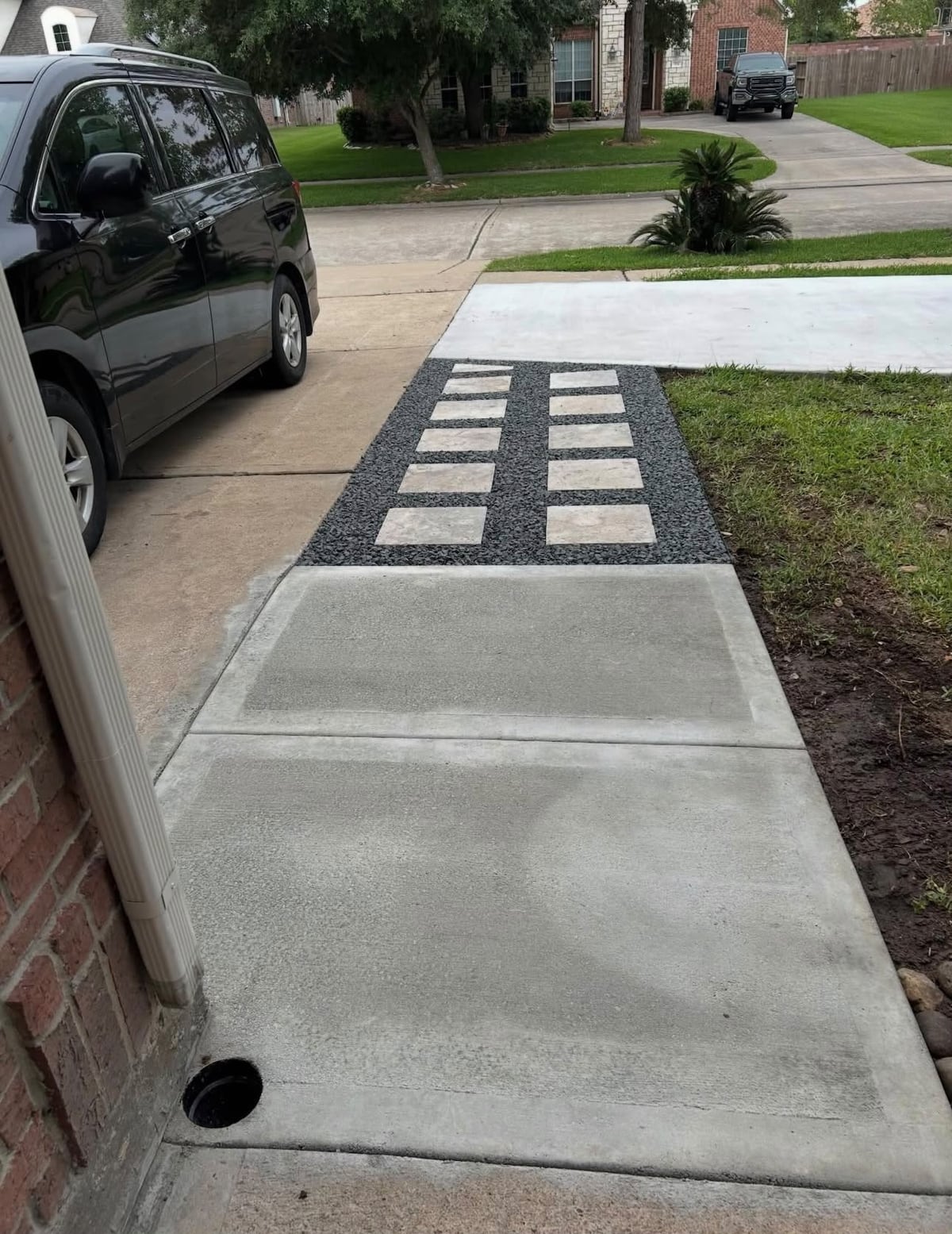 Concrete front walk connected to a stone-and-gravel path beside a driveway