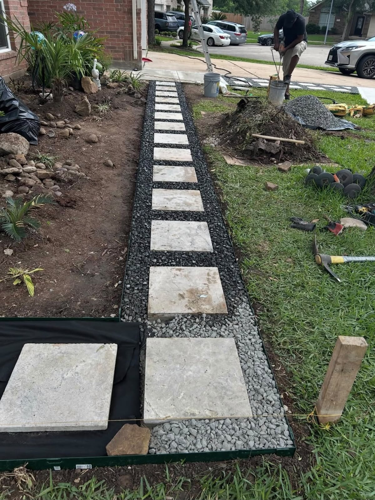 Stepping-stone walkway being laid in dark gravel beside a Houston home