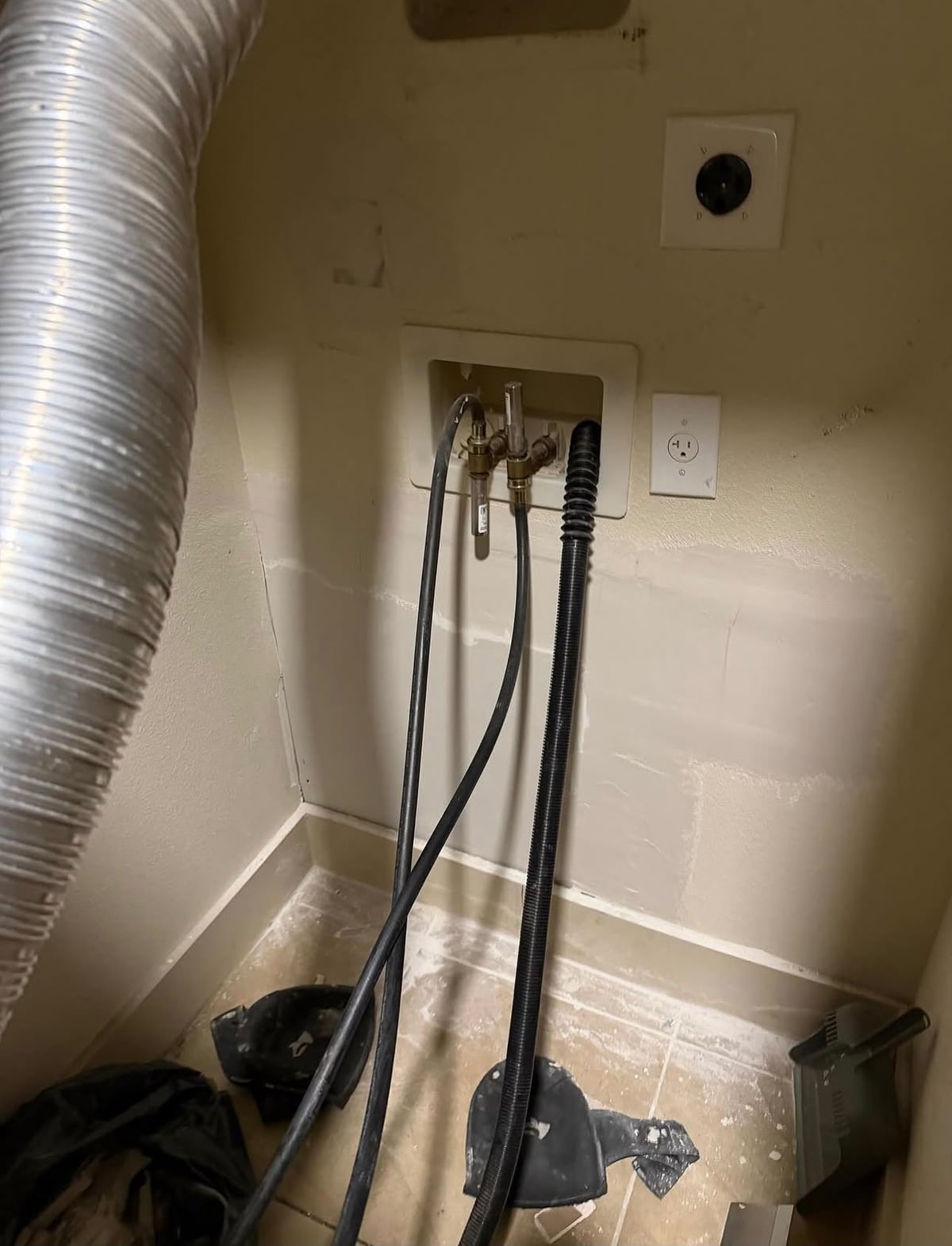 Utility room wall after drywall patching around washer connections
